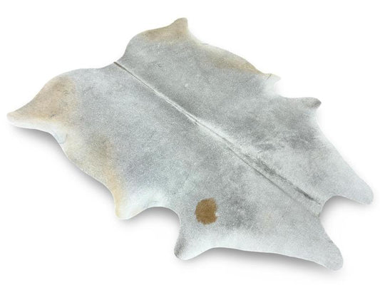Light grey color cowhide with light brown back legs and a brown spot